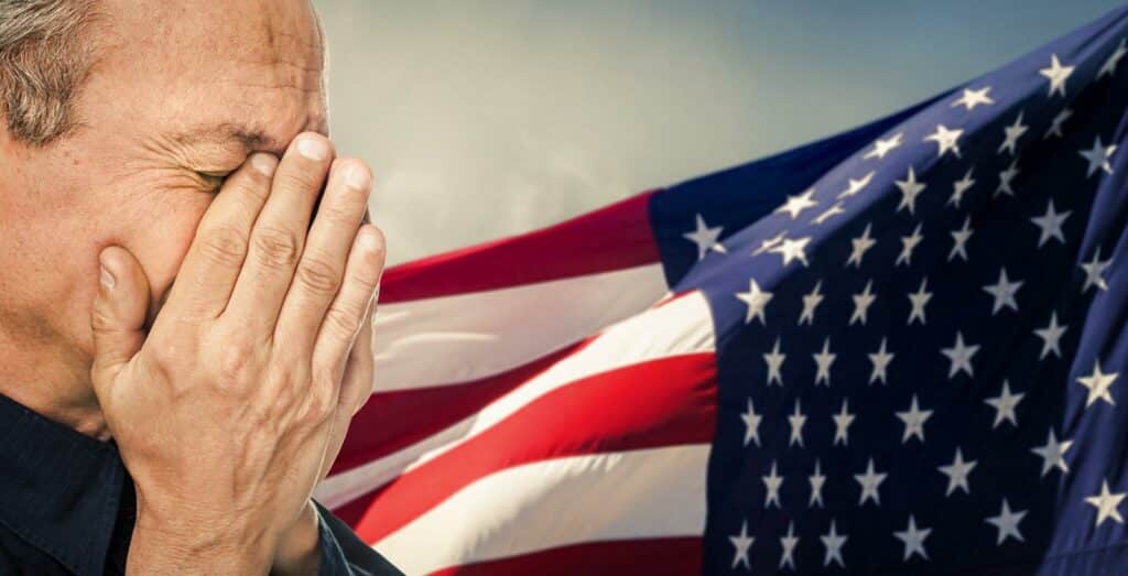 An elderly man with face closed by hand on USA flag background