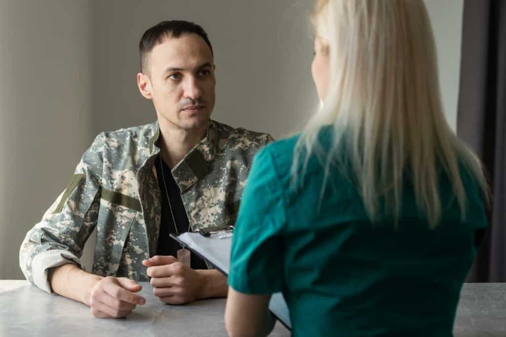Female doctor and worried military officer discussing about problems he has during psychotherapy treatment